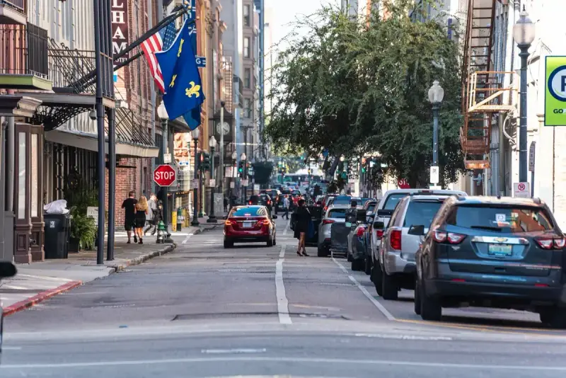 Downtown New Orleans street with flags, brick buildings and parked cars