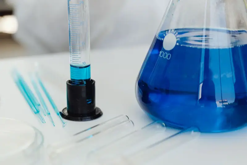 Erlenmeyer flask of blue liquid beside test tubes and a graduated cylinder