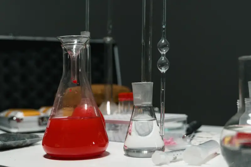 Laboratory glassware holding red and clear liquids on a bench