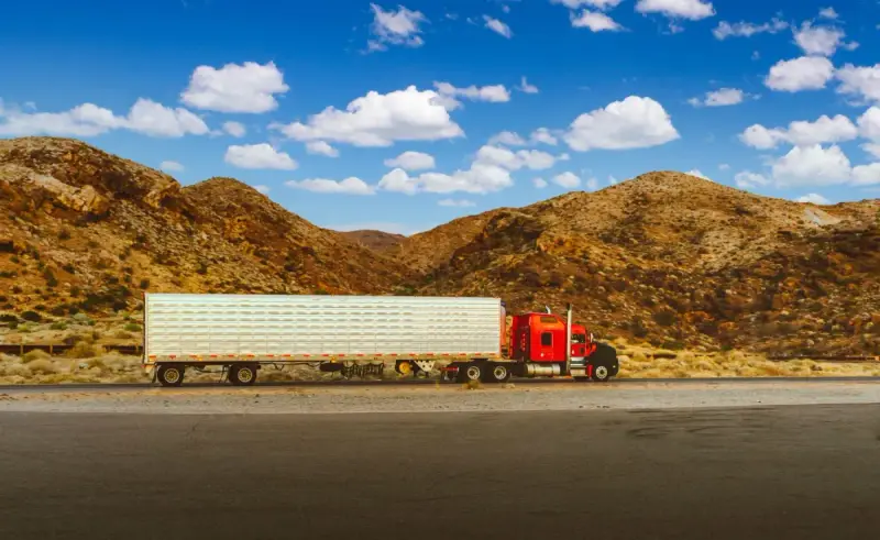 Red semi-truck traveling on a Nevada desert highway