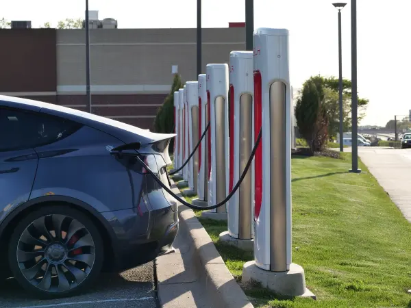 Electric passenger car connected to one of a row of charging stations