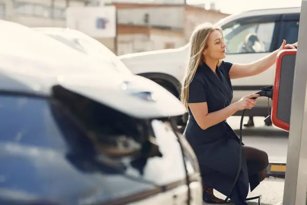 Woman connecting an electric car at a street-side charging station