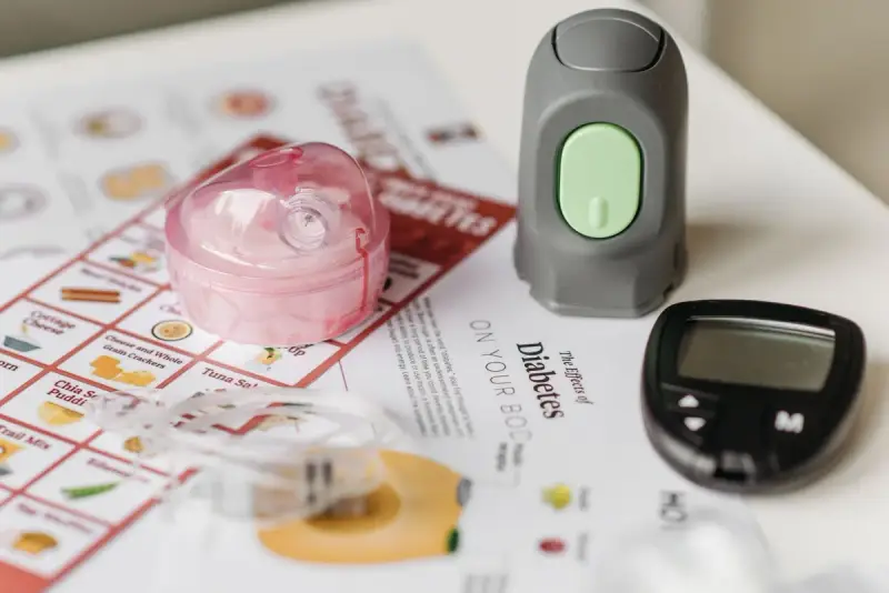 Blood glucose meter and monitoring supplies laid out beside diabetes education materials