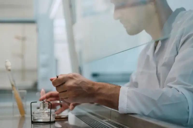 Scientist working with care behind a glass shield at a lab bench