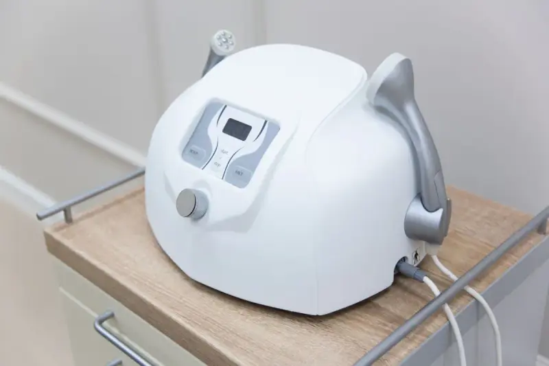 A facial device stands on a white cabinet.