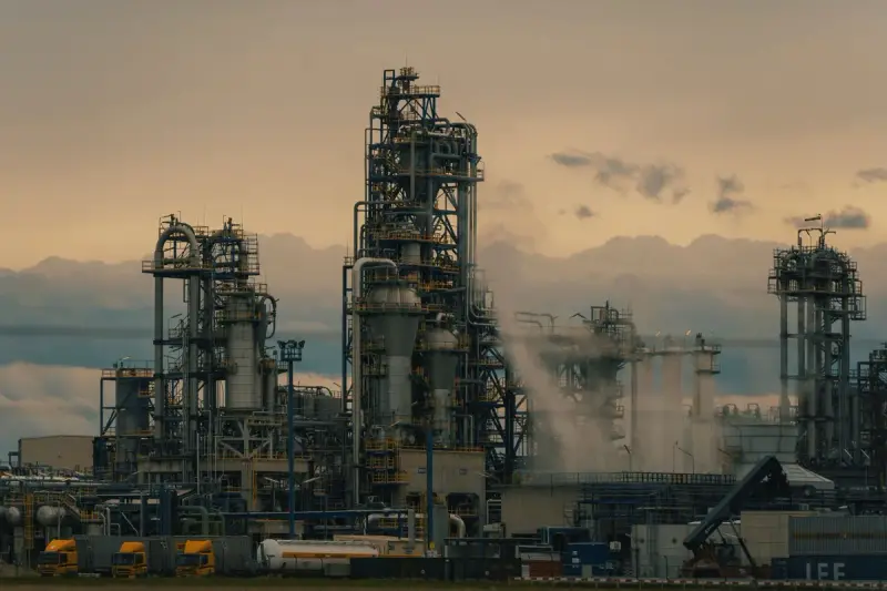 Refinery tower with pipework and heat exchangers against a pale sky