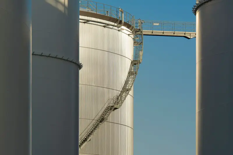 Tall storage tanks with a steel staircase against a blue sky