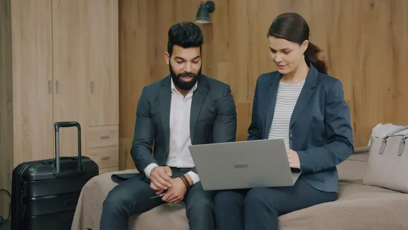 Two professionals reviewing a laptop together in a hotel suite