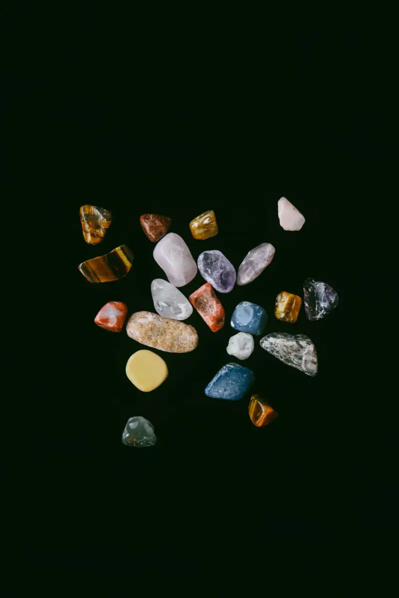 Polished colored gemstones of many hues scattered on a black backdrop