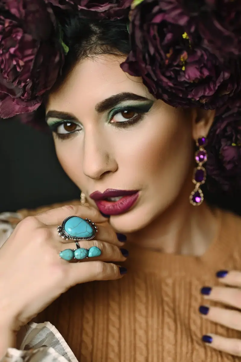 Woman with a floral headpiece wearing turquoise cocktail rings and amethyst drop earrings