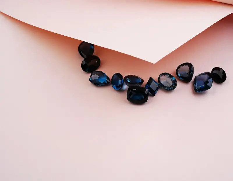 Faceted blue sapphires laid out on folded pink parcel paper