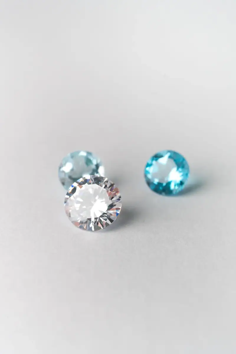 Loose blue topaz and white faceted gemstones on a white surface