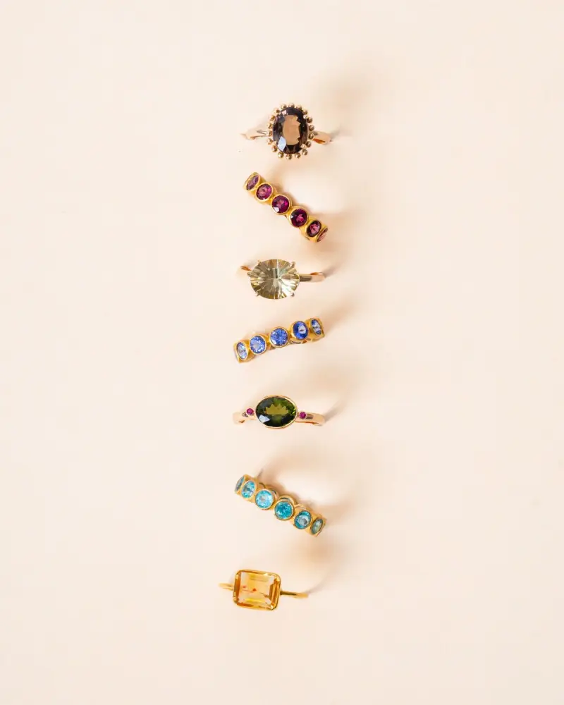 Row of gold rings set with garnet, peridot, sapphire, emerald and citrine
