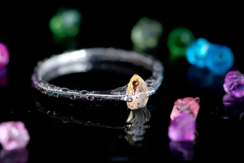 Diamond ring on a reflective surface surrounded by colorful rough gemstones