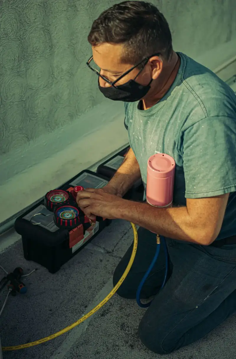 Technician kneeling outdoors to service an air conditioning system