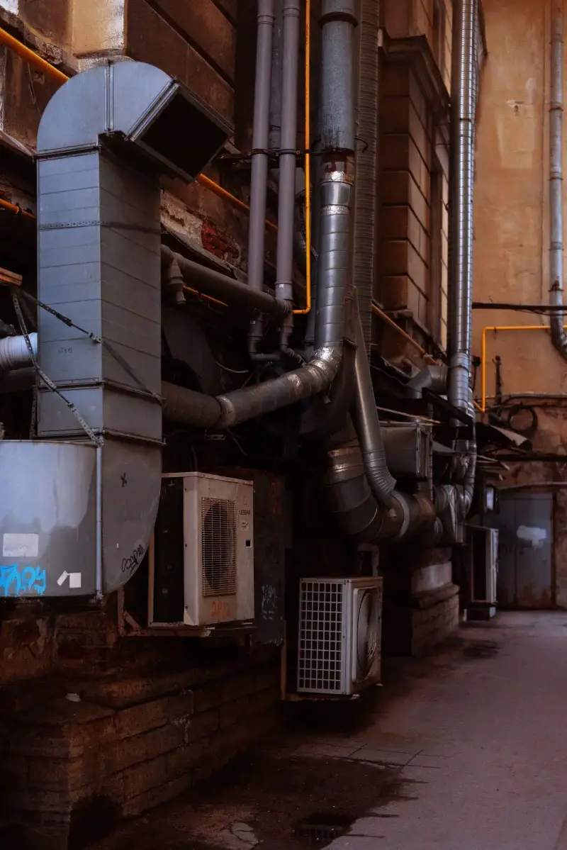 Air conditioning units and refrigerant pipes on the back wall of a building