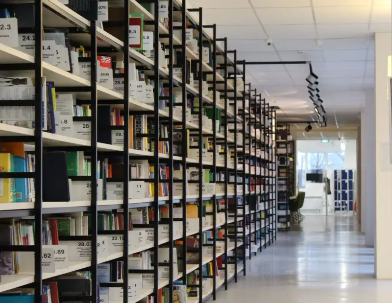 Modern library aisle between rows of organized, well-lit bookshelves