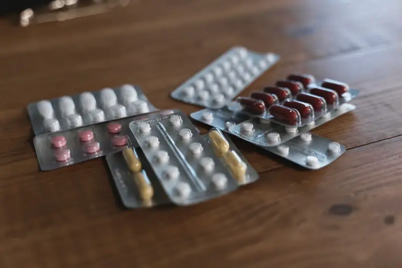 Several blister packs of white, pink and brown tablets on a wooden table