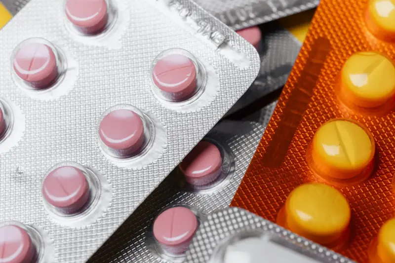 Close-up of pink and orange tablets sealed in silver blister packs