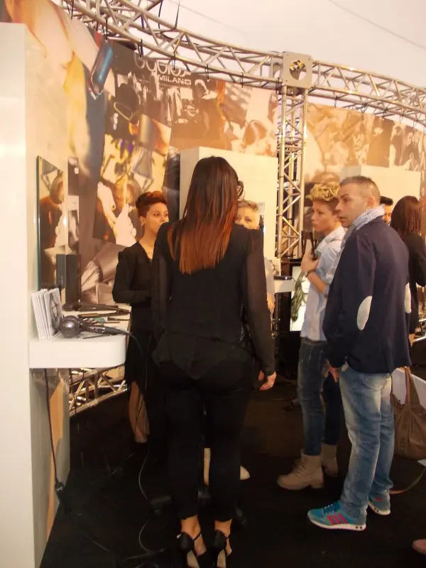 Visitors and a female beauty professional discussing products at Cosmoprof Bologna