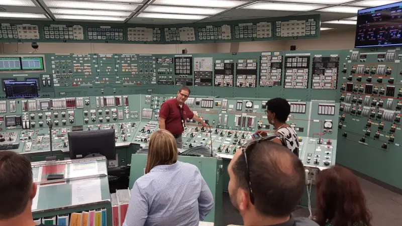 Resident inspector presenting to a group inside a nuclear plant control room simulator