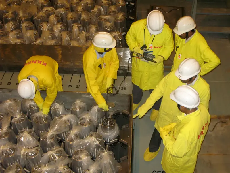 Inspectors measuring a nuclear fuel assembly with handheld equipment