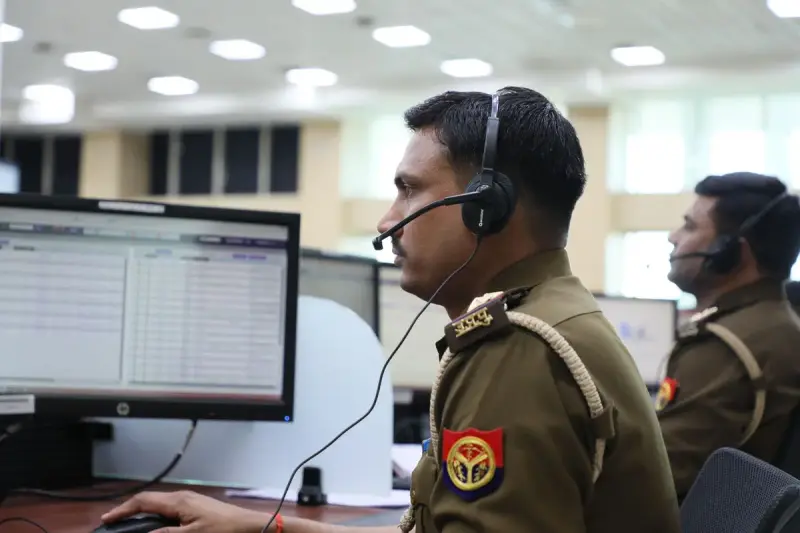 Uniformed dispatchers wearing headsets working at computer stations in an emergency dispatch center