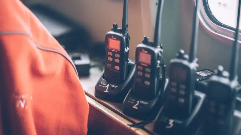 Four handheld two-way radios standing in their charging stations