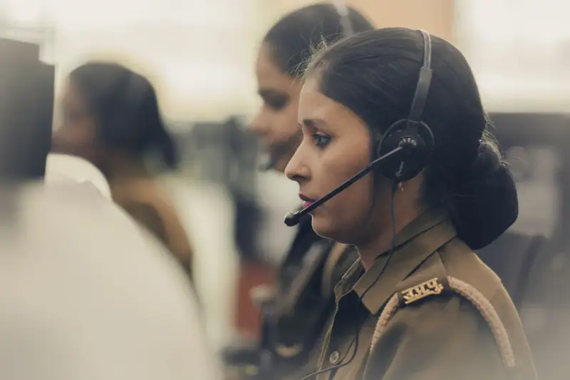 Woman dispatcher with a headset handling calls at a computer station