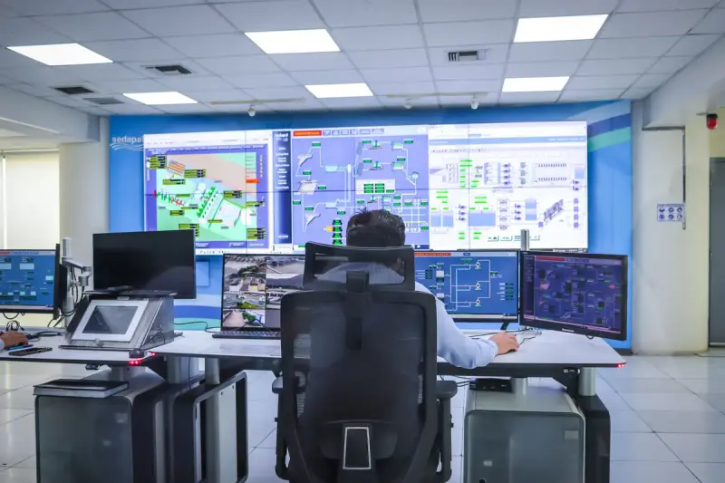 Operator working in a modern control room with a wall of monitoring screens