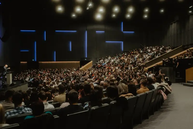 Packed auditorium seen from the back during a conference presentation