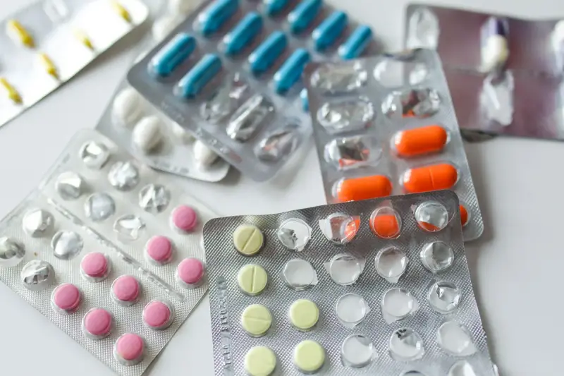 Assorted blister packs of colorful tablets and capsules on a white surface