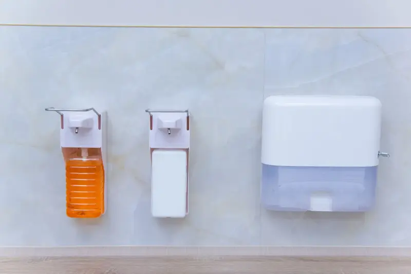 Wall-mounted soap, sanitizer and paper towel dispensers in a medical room