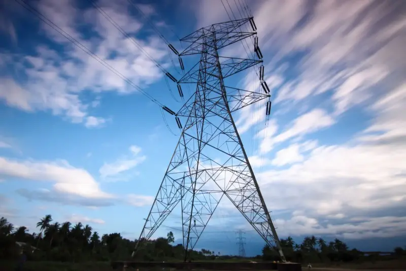 High-voltage transmission tower under a dramatic cloudy sky