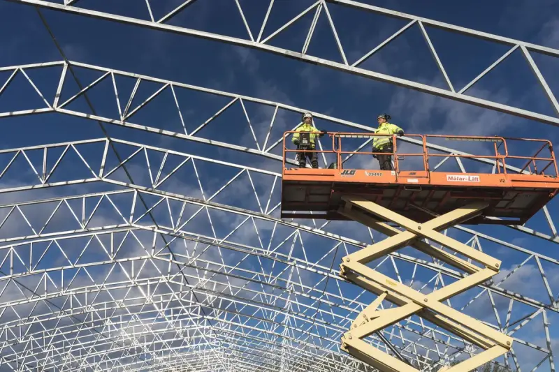 Two workers standing on a raised scissor lift at a construction site