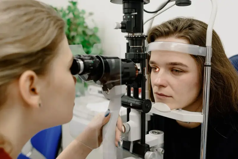 Eye care professional examining a young woman's eye with a slit lamp