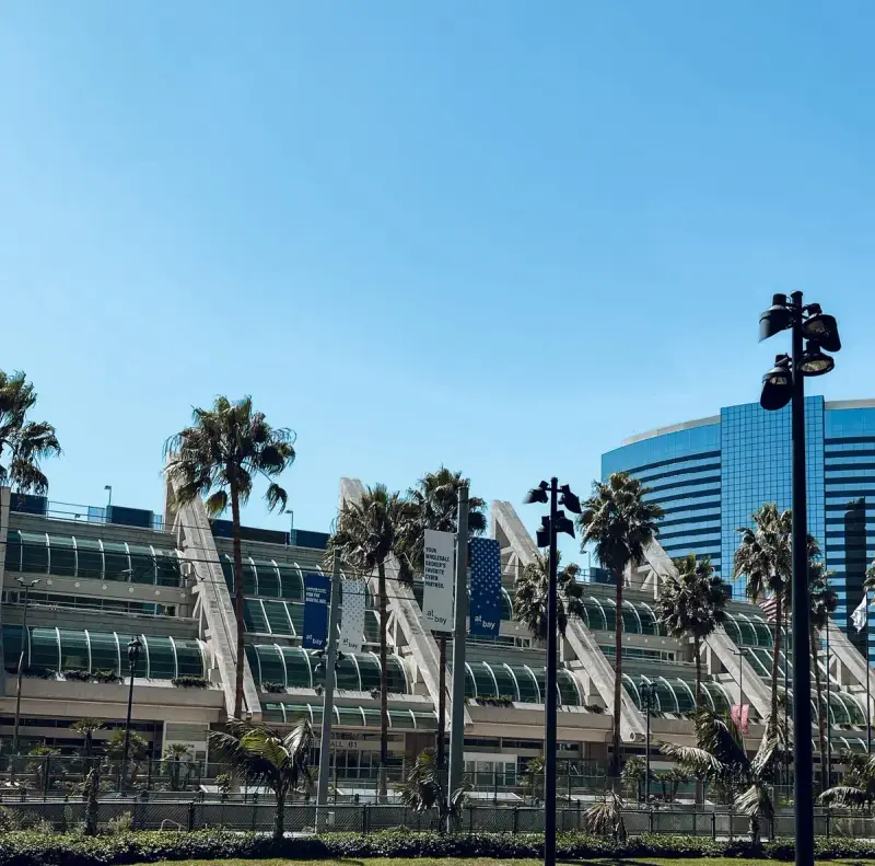 San Diego Convention Center exterior with sail-like masts and palm trees under blue sky