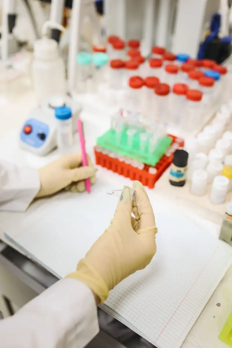 Scientist in a white lab coat and gloves working with samples at a lab bench