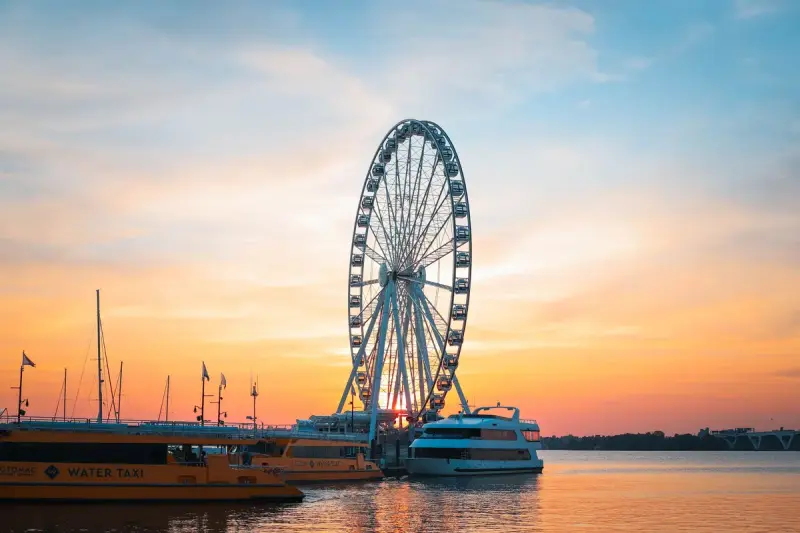 Ferris wheel and water taxis at National Harbor at sunset