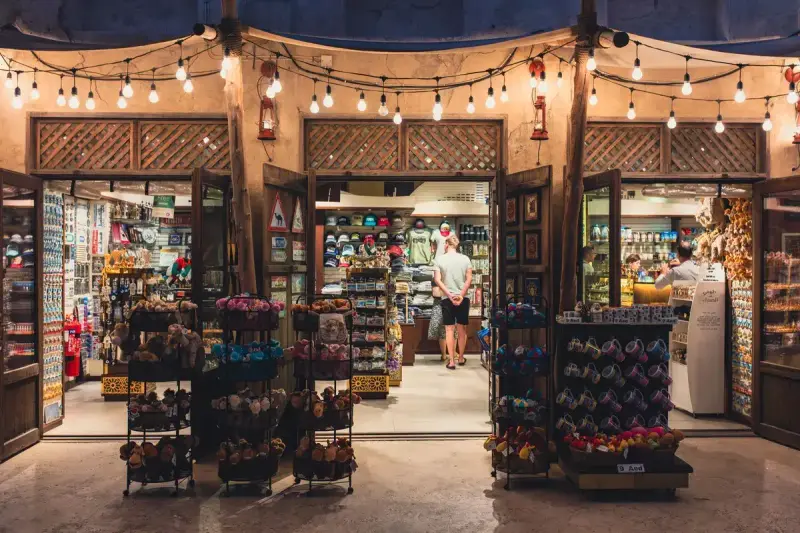 Illuminated souvenir shop entrance under string lights with racks of gifts outside