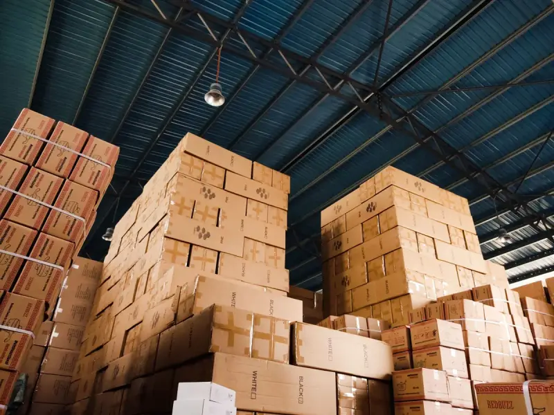 Towering stacks of cardboard cartons under a blue warehouse roof