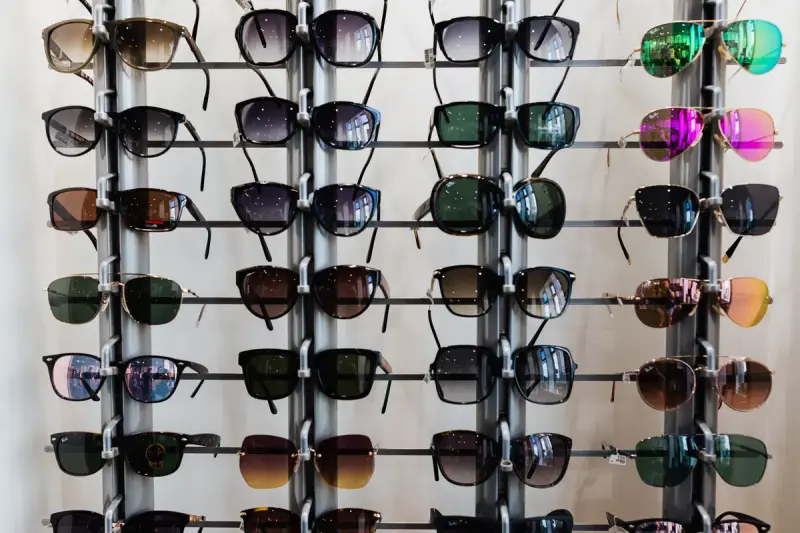 Rows of dark and mirrored sunglasses on a metal rack display