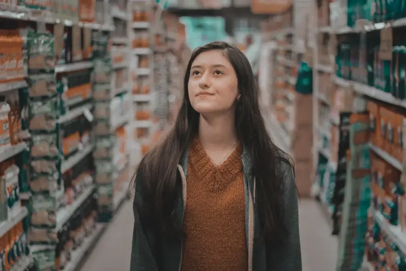 Woman looking up at high shelves while walking a store aisle