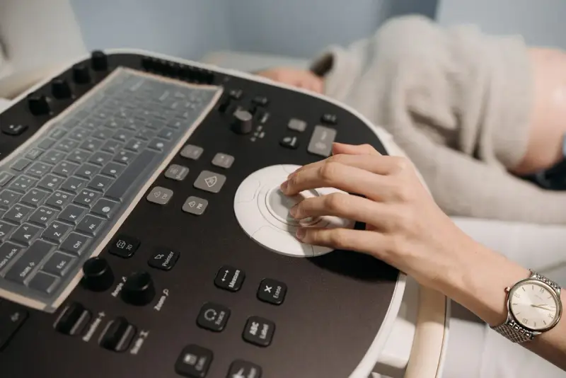 Close view of a clinician's hand on the trackball of an ultrasound control panel