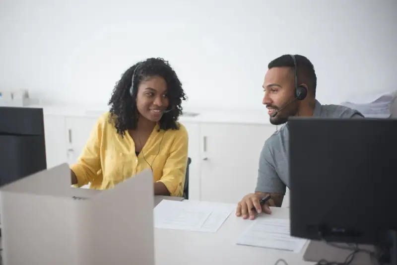 Two support agents in headsets working side by side at computers