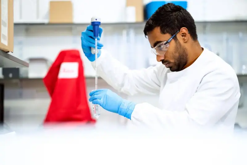 Scientist holding a pipette and focusing on a sample