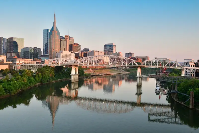 Nashville skyline and pedestrian bridge reflected in the Cumberland River at sunrise