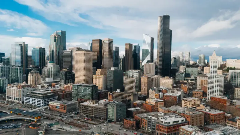 Aerial view of downtown Seattle skyscrapers under a bright sky with scattered clouds