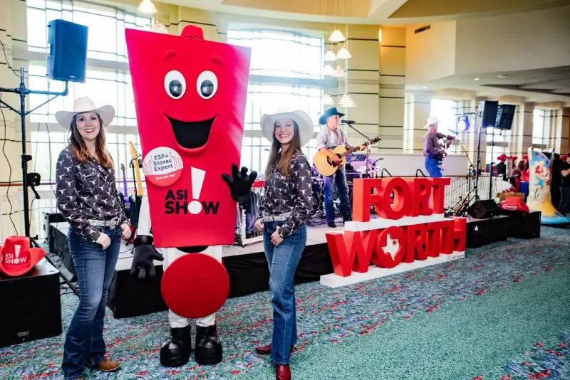Show mascot and cowboy-hatted greeters beside a red Fort Worth sign at the ASI Show