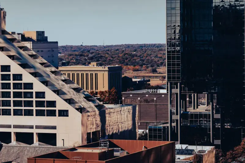 Downtown Fort Worth towers and rooftops with green hills on the horizon